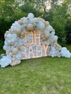 Large outdoor balloon arch with glowing “OH BABY” letters in cream tones by Iconic Events Edmonton. Making Every Event in Edmonton Iconi