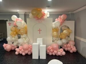 Pastel balloon arch setup with cross and “God Bless Gina” theme for a christening event by Iconic Events Edmonton. Making Every Event in Edmonton Iconic.