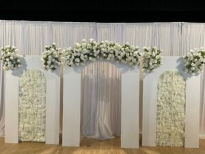 Elegant white floral arch backdrop with roses for a wedding or special celebration by Iconic Events Edmonton. Making Every Event in Edmonton Iconic.